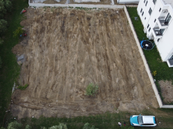 Prime Ulcinj investment: Spacious cleared lot beside modern white apartments, surrounded by lush trees. Exclusive at montenegro-listings.me by ekosphere doo.