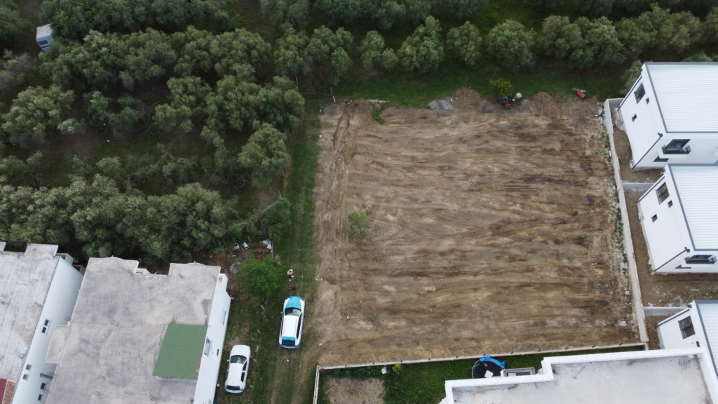 Prime investment opportunity: cleared land between two white buildings in Ulcinj, Montenegro—ideal for new development. Montenegro-listings.me by ekosphere doo.