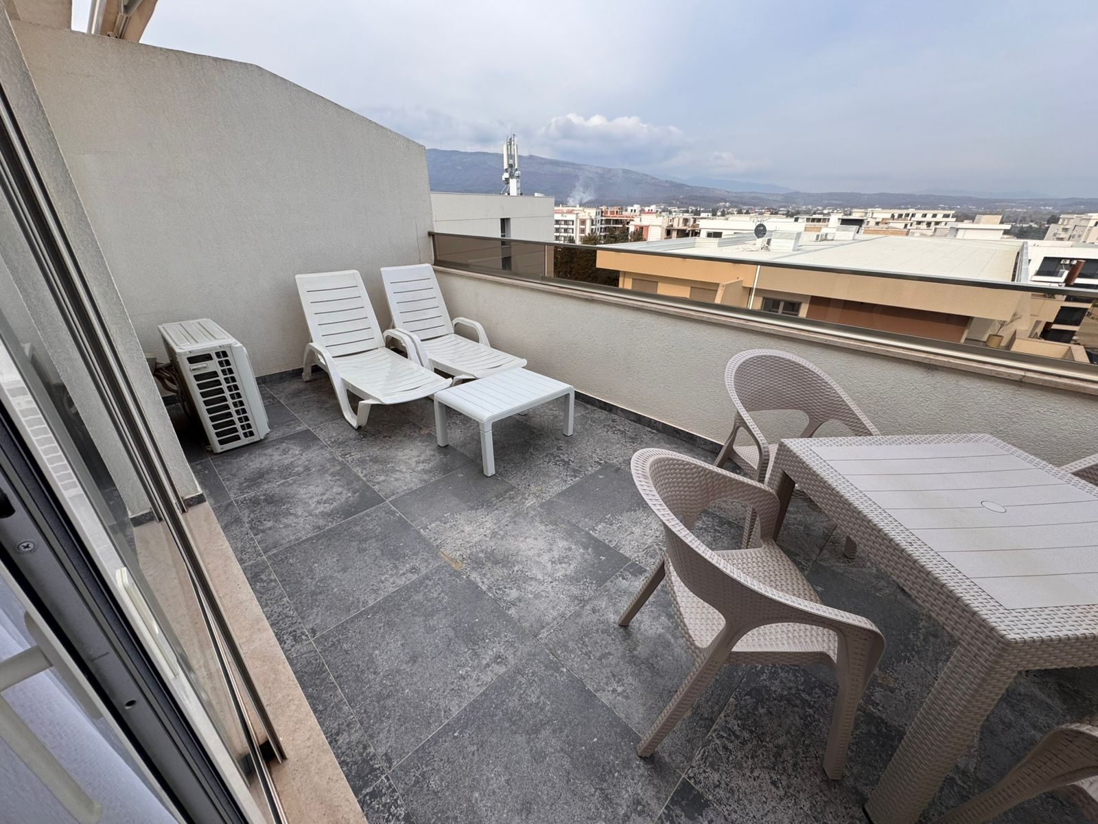 Stylish rooftop terrace in Ulcinj: lounge chairs, dining area, AC unit, and city views. Investment via montenegro-listings.me (ekosphere doo).