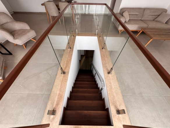 Elegant dark-wood staircase with glass railings in a stylish Ulcinj living area—ideal Montenegro investment. eksosphere doo project.