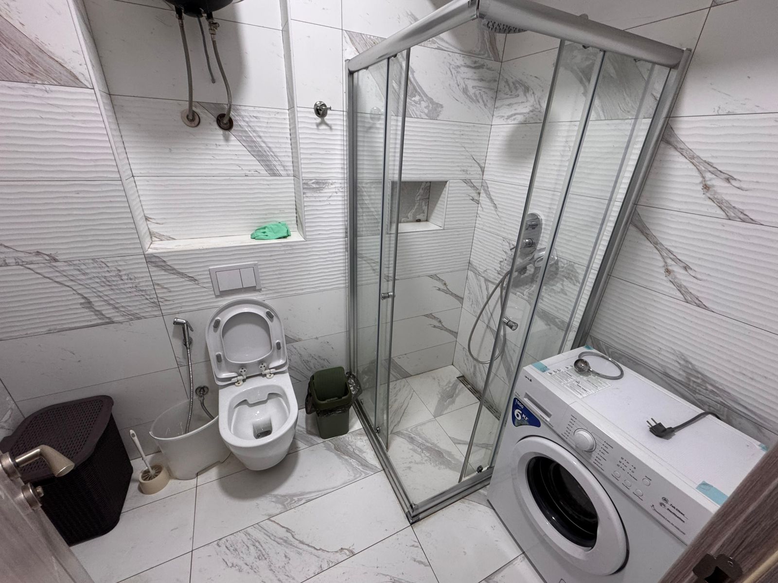 Elegant Ulcinj bathroom with white marble, premium fixtures, laundry area. Invest in top Montenegro property at montenegro-listings.me.