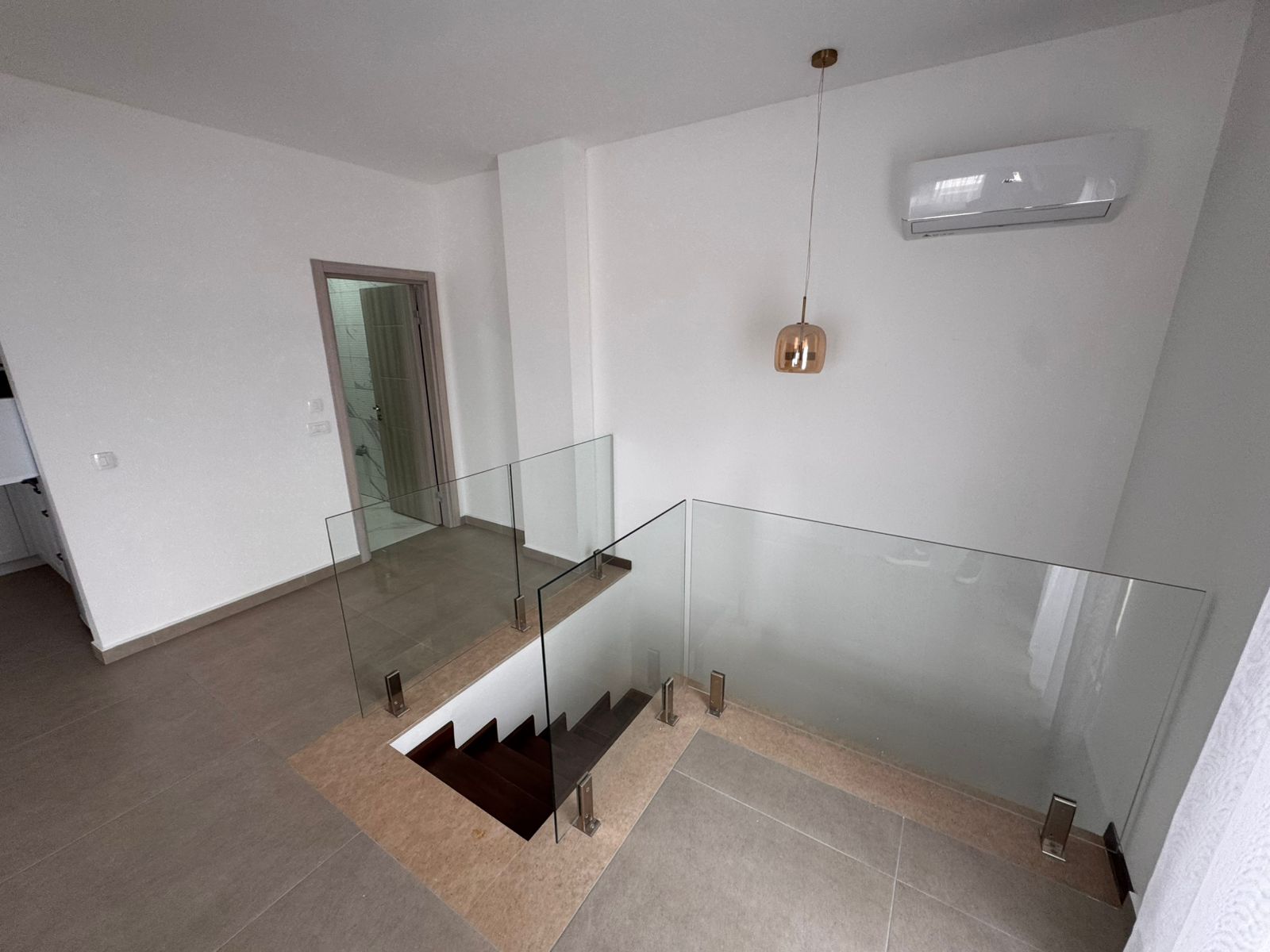 Sophisticated Ulcinj property: sleek glass-railed staircase, beige tile, AC, and modern bathroom. Invest with ekosphere doo on montenegro-listings.me.