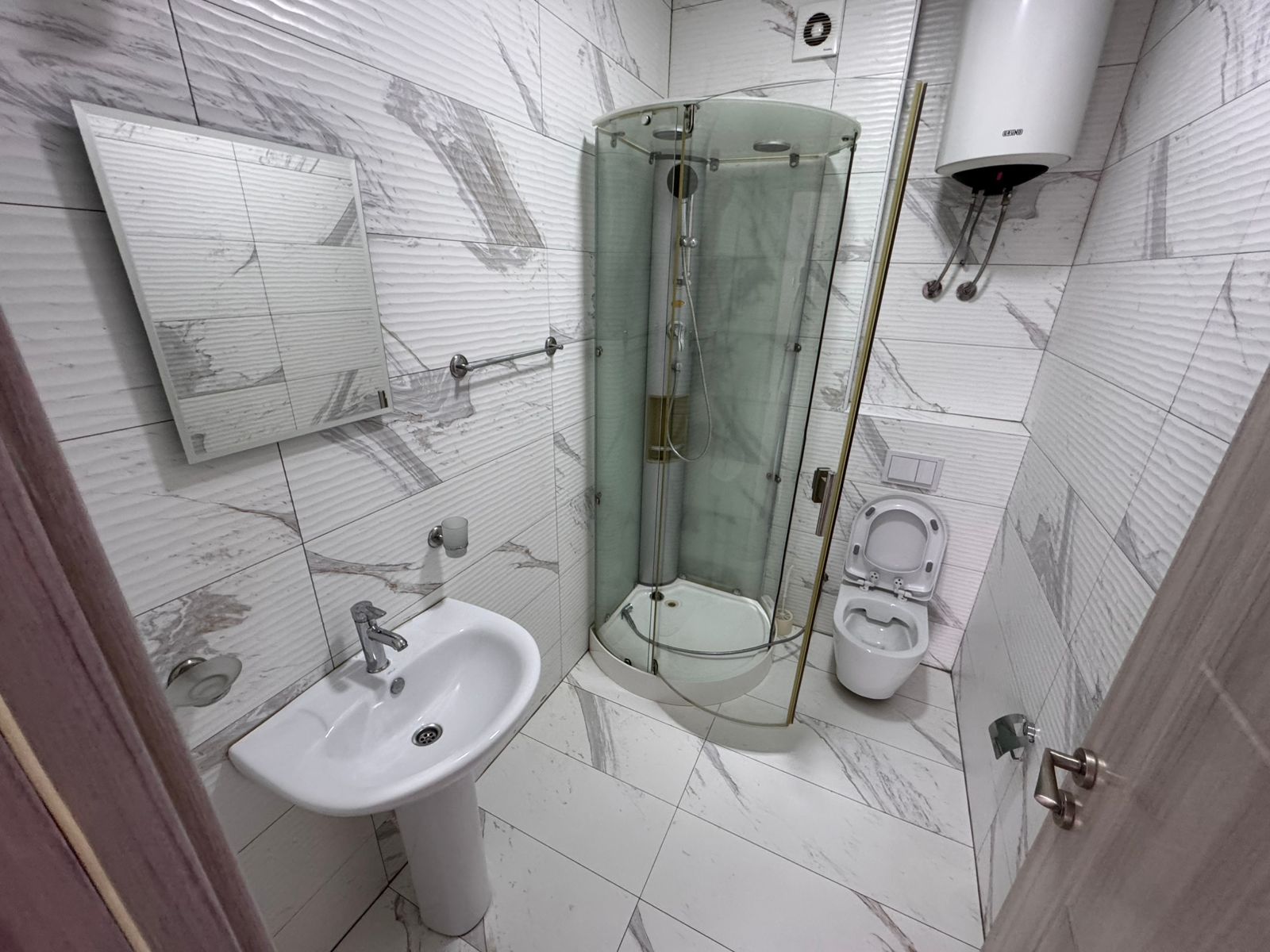 Elegant Ulcinj bathroom with white marble tiles, modern fixtures, premium shower, bidet&mdash;prime Montenegro real estate by ekosphere doo.