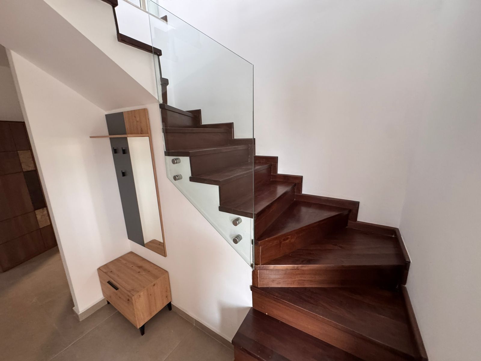Stylish wooden staircase with glass railing, tiled flooring, and modern accents&mdash;an Ulcinj investment via montenegro-listings.me by ekosphere doo.
