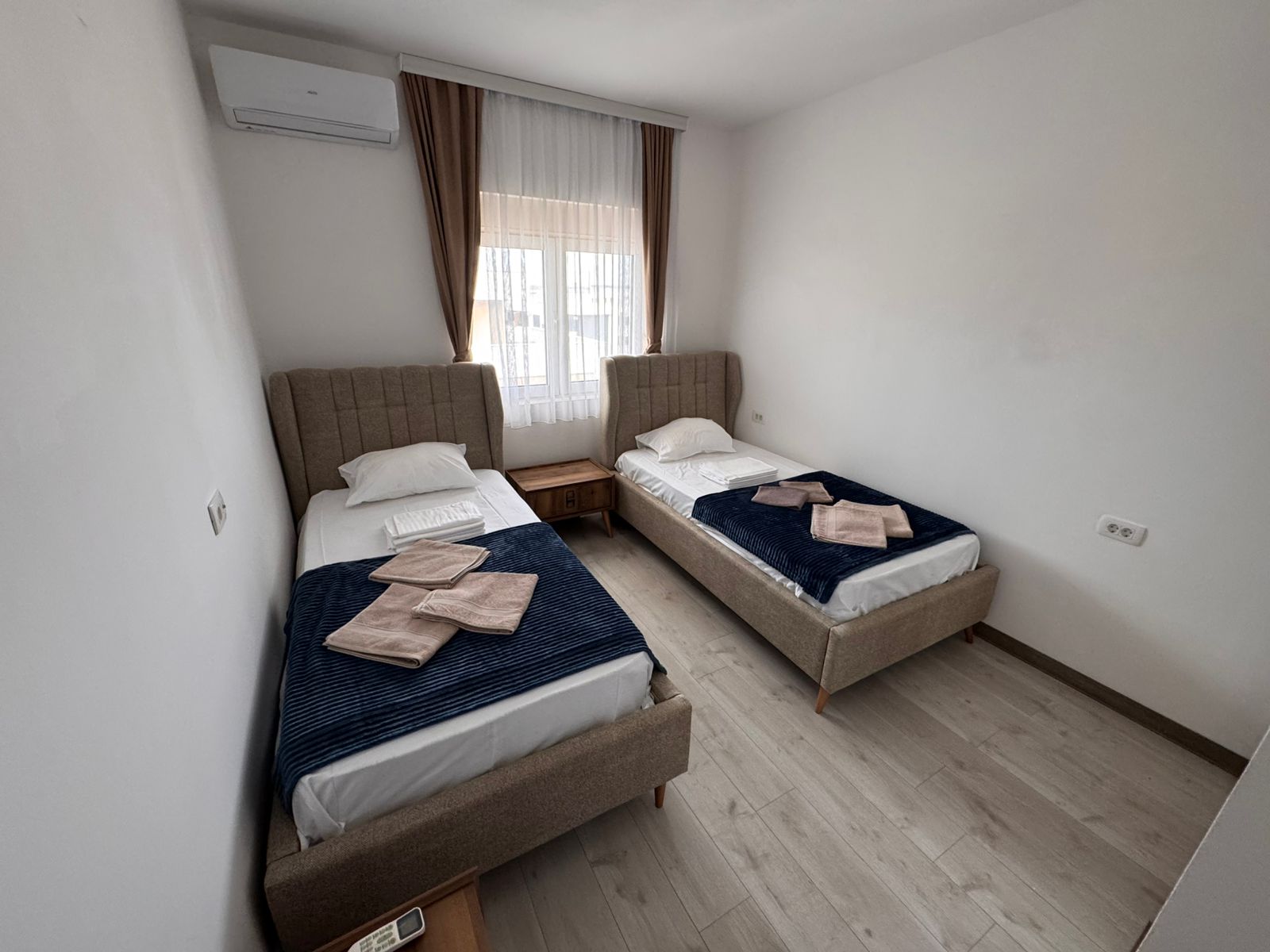 Attractive Ulcinj hotel room: 2 single beds, navy blankets, modern wood accents. Ideal Montenegro investment. Ekosphere doo project.