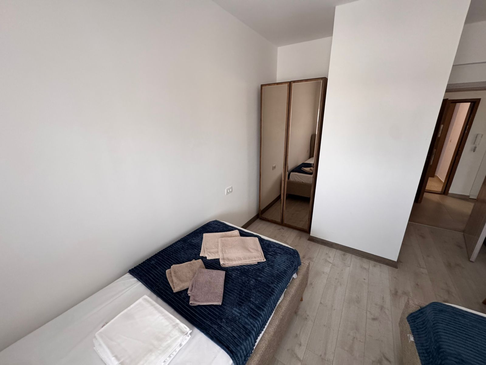 Elegant Ulcinj bedroom: twin beds, dark blue linens, mirrored wardrobe, light wood floors&mdash;ideal real estate investment on montenegro-listings.me by ekosphere doo.