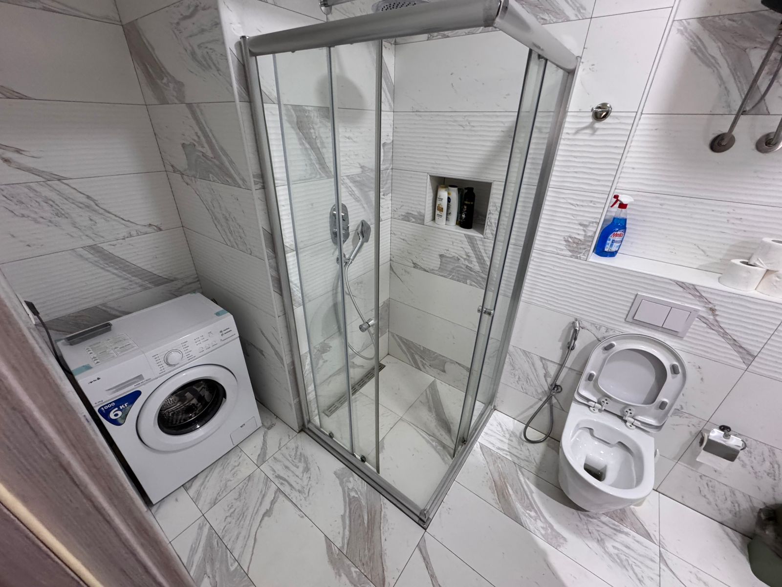 Luxurious Ulcinj bathroom with marble tiles, glass shower, washer, bidet. Invest in Montenegro real estate via montenegro-listings.me.