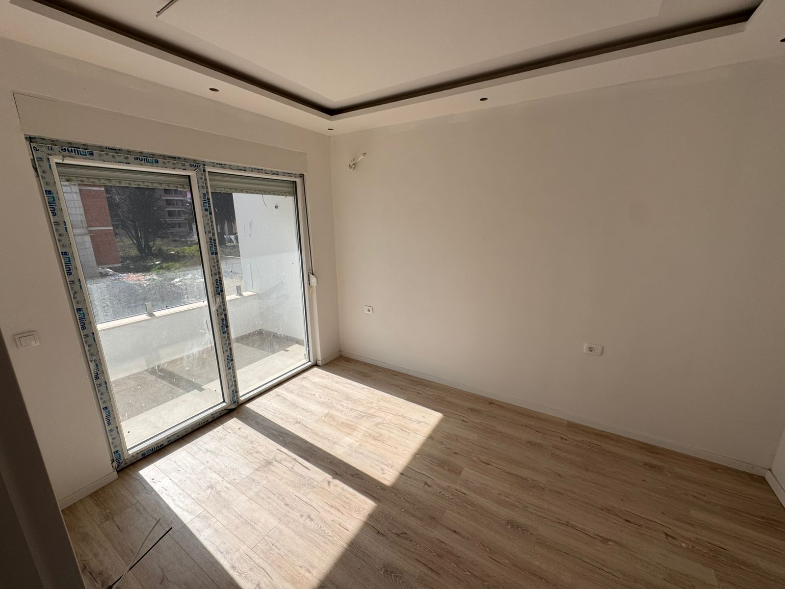 Bright, modern Ulcinj apartment with light wood floors, sunlit balcony, and stylish recessed lighting. Exclusive at montenegro-listings.me by ekosphere doo.