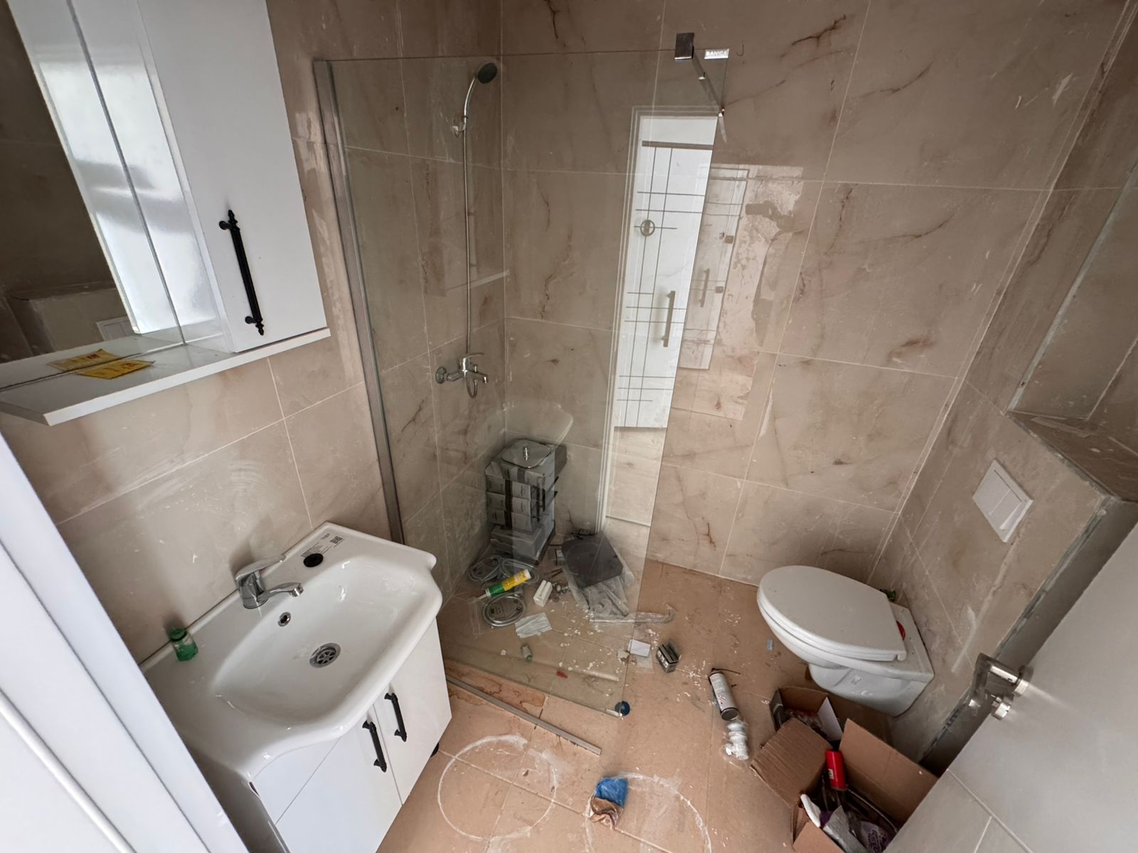 Modern bathroom in Ulcinj with beige tiles, glass shower, sleek fixtures&mdash;perfect for property investment at montenegro-listings.me by ekosphere doo.
