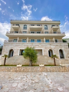 Prime investment opportunity: elegant 4-story beige residence with arched entrances, balconies, and palm landscaping in Ulcinj. Listed by montenegro-listings.me—an ekosphere doo project.