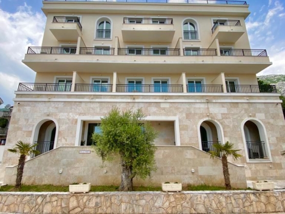 Prime investment opportunity: elegant 4-story beige residence with arched entrances, balconies, and palm landscaping in Ulcinj. Listed by montenegro-listings.me&mdash;an ekosphere doo project.