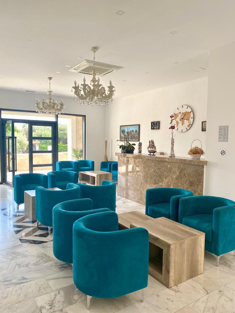 Elegant lounge in Ulcinj with teal armchairs, marble floors, chandeliers; prime real estate on montenegro-listings.me by ekosphere doo.