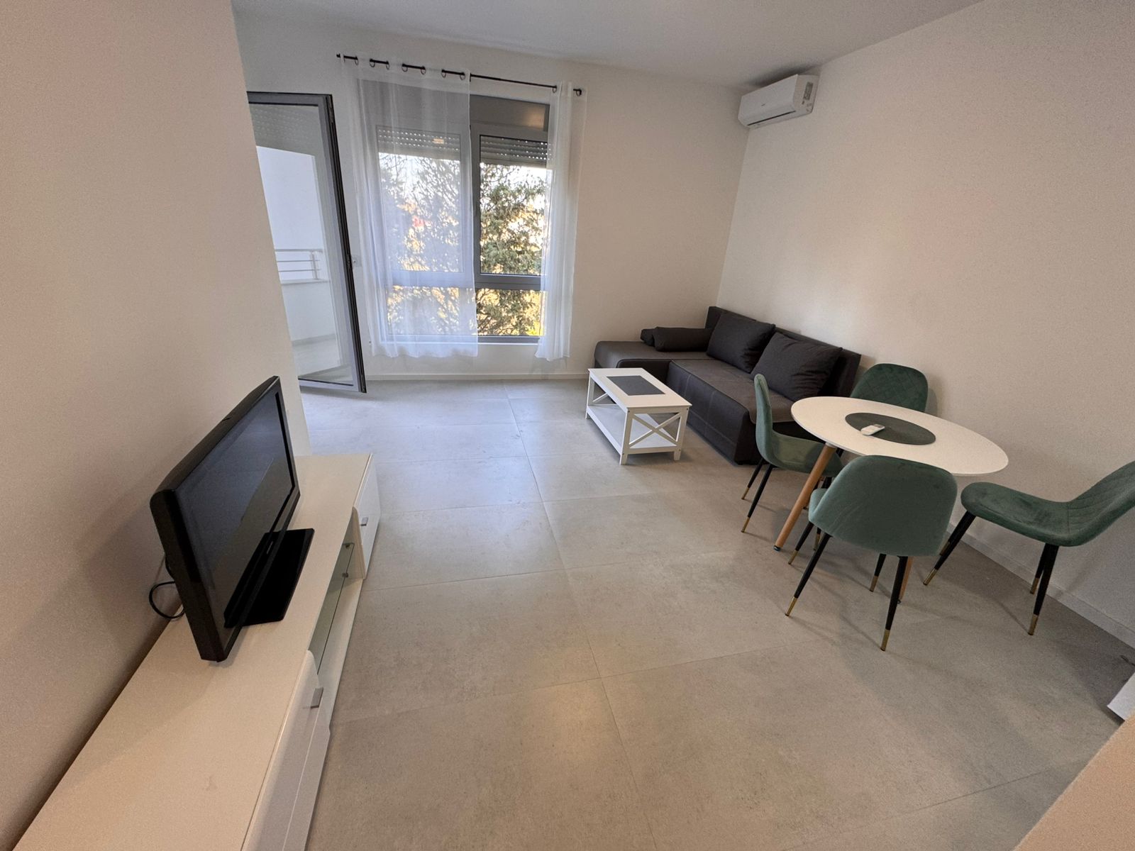 Spacious modern living room in Ulcinj with sleek black sofa, dining area, large windows&mdash;ideal Montenegro investment at montenegro-listings.me.