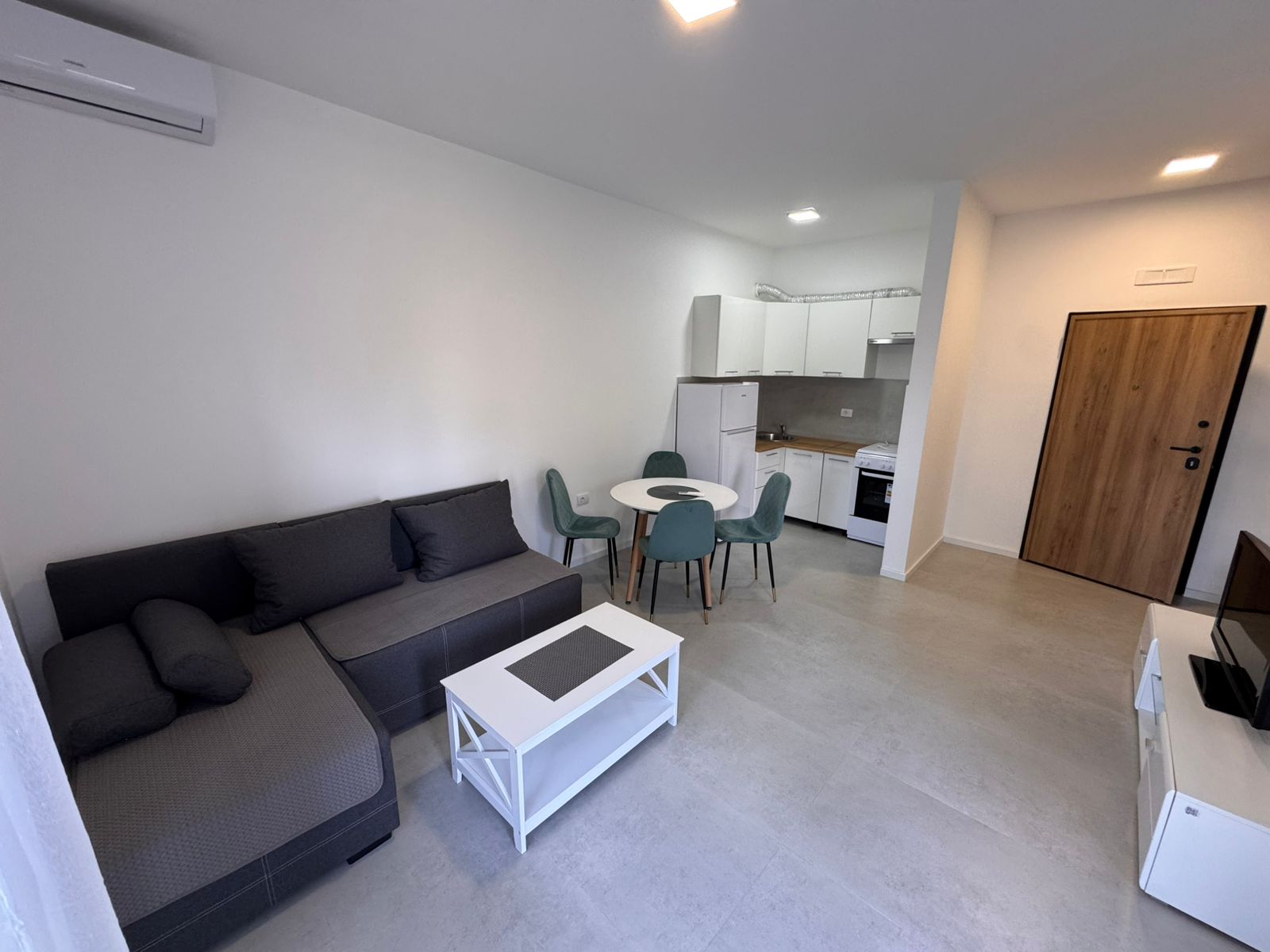 Modern Ulcinj studio: stylish gray sofa, bright kitchen, dining for four. Prime property investment at montenegro-listings.me by ekosphere doo.