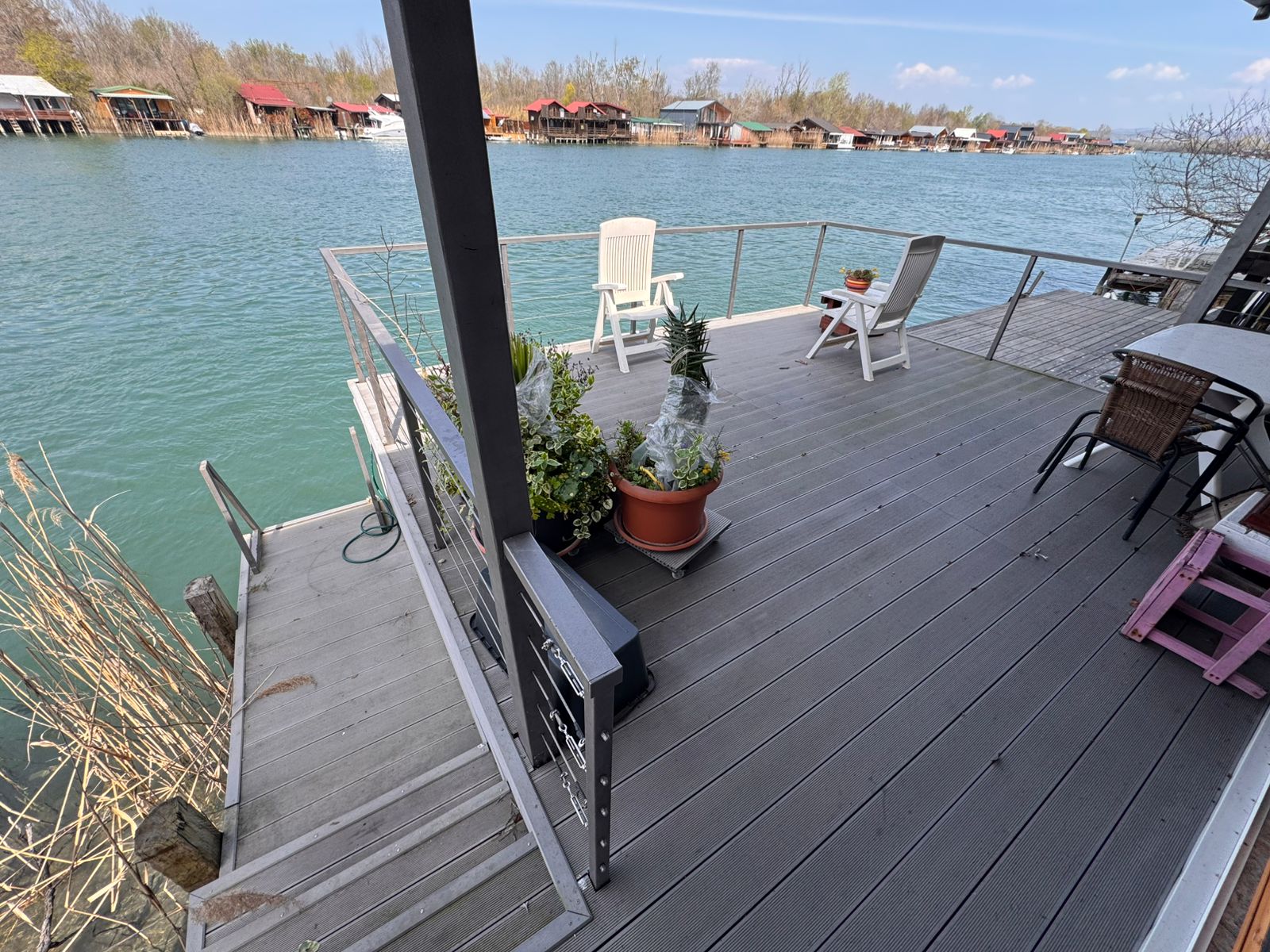 Stunning Ulcinj waterfront deck with metal railings, white chairs, potted plants, and scenic views&mdash;invest via montenegro-listings.me by ekosphere doo.