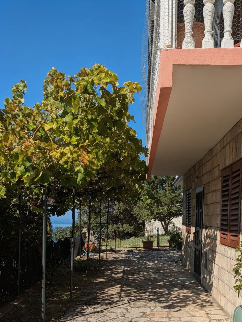 Charming Ulcinj home for sale: stone path, balcony views, lush grapevines, sea & greenery. Exclusive with montenegro-listings.me.