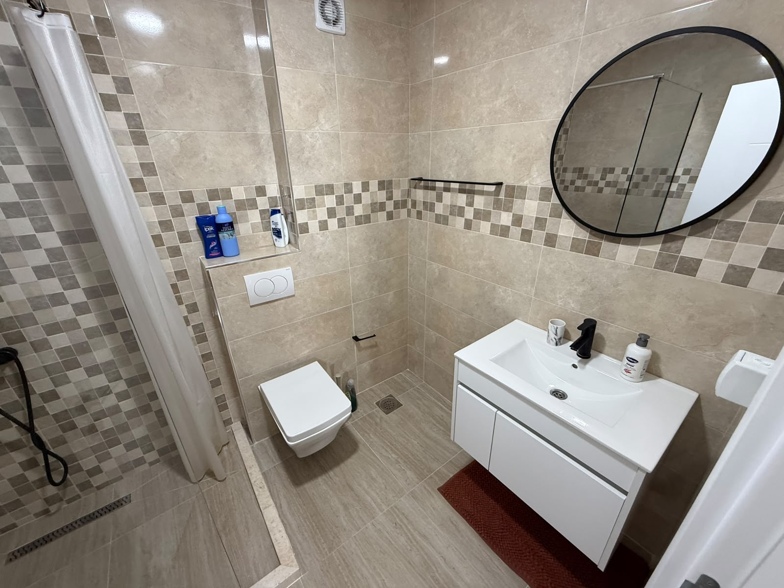 Contemporary bathroom in Ulcinj with designer tiles, wall-mounted toilet, sleek sink cabinet, ideal for investment at montenegro-listings.me.