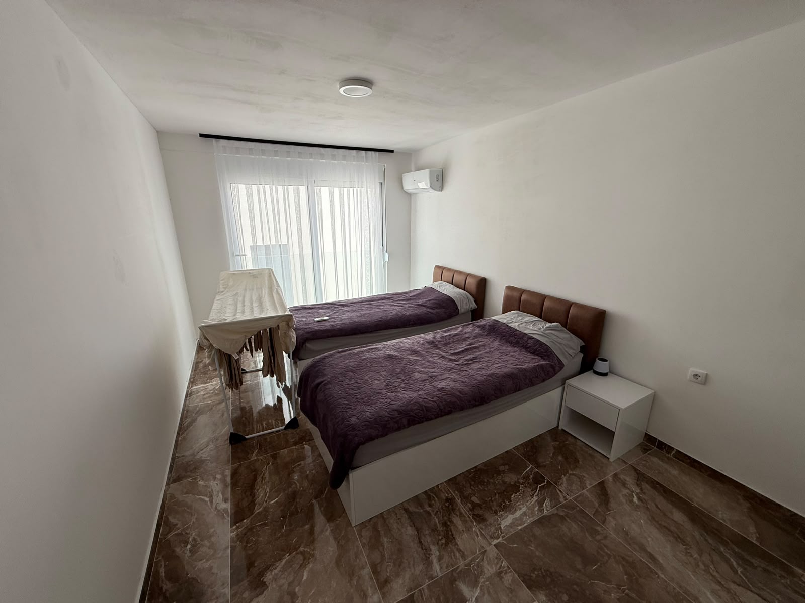 Elegant minimalist bedroom in Ulcinj: twin beds, modern finishes, bright windows&mdash;an ideal Montenegro investment by ekosphere doo.