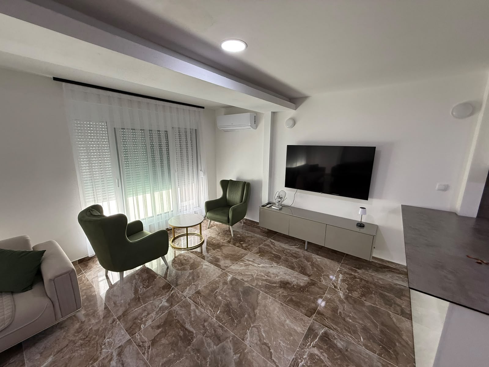 Elegant Ulcinj living room with marble floors, bright seating, and large windows&mdash;an ideal Montenegro investment by ekosphere doo.