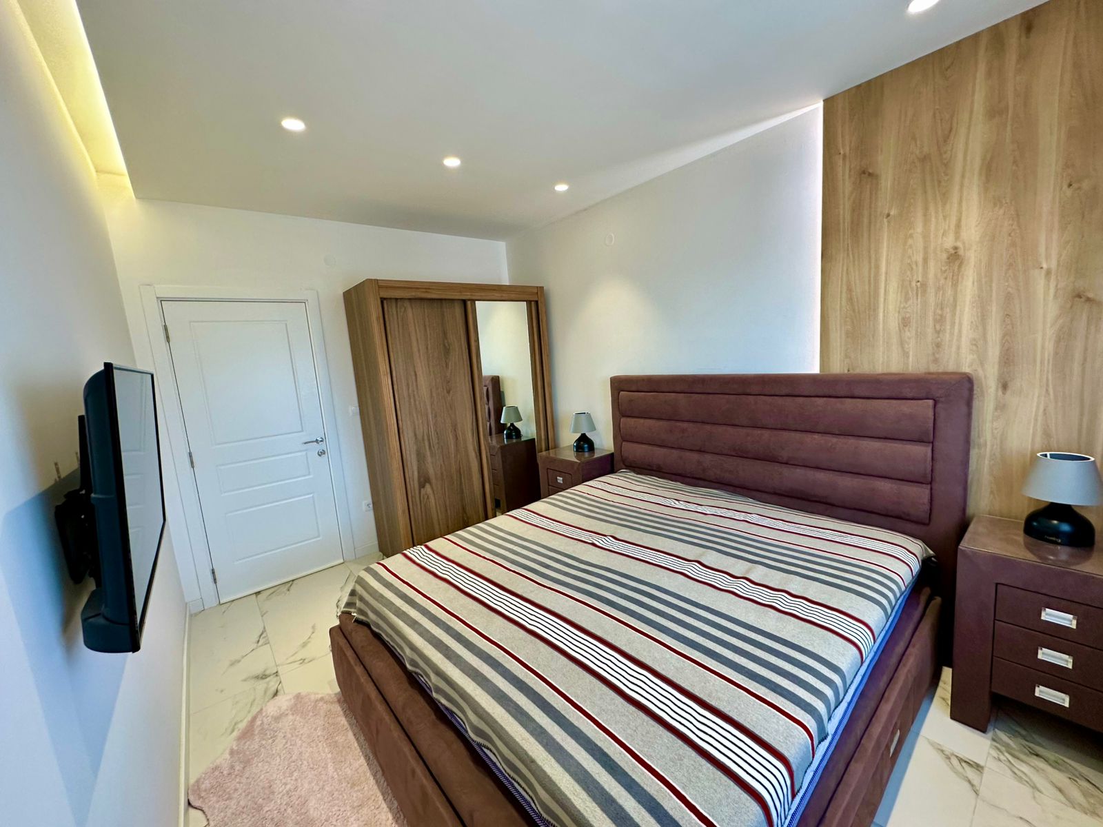 Elegant Ulcinj bedroom with double bed, mirrored wardrobe, TV, and premium lighting&mdash;ideal Montenegro investment, montenegro-listings.me by ekosphere doo.