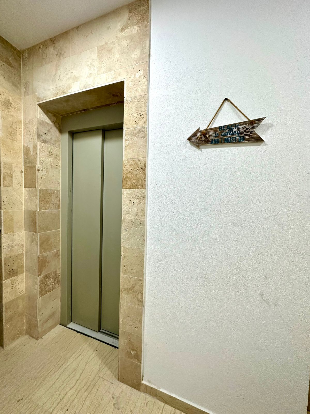 Modern elevator with sleek metallic doors, elegant beige stone accent, and textured flooring&mdash;premium Ulcinj apartment living by montenegro-listings.me, a project of ekosphere doo.