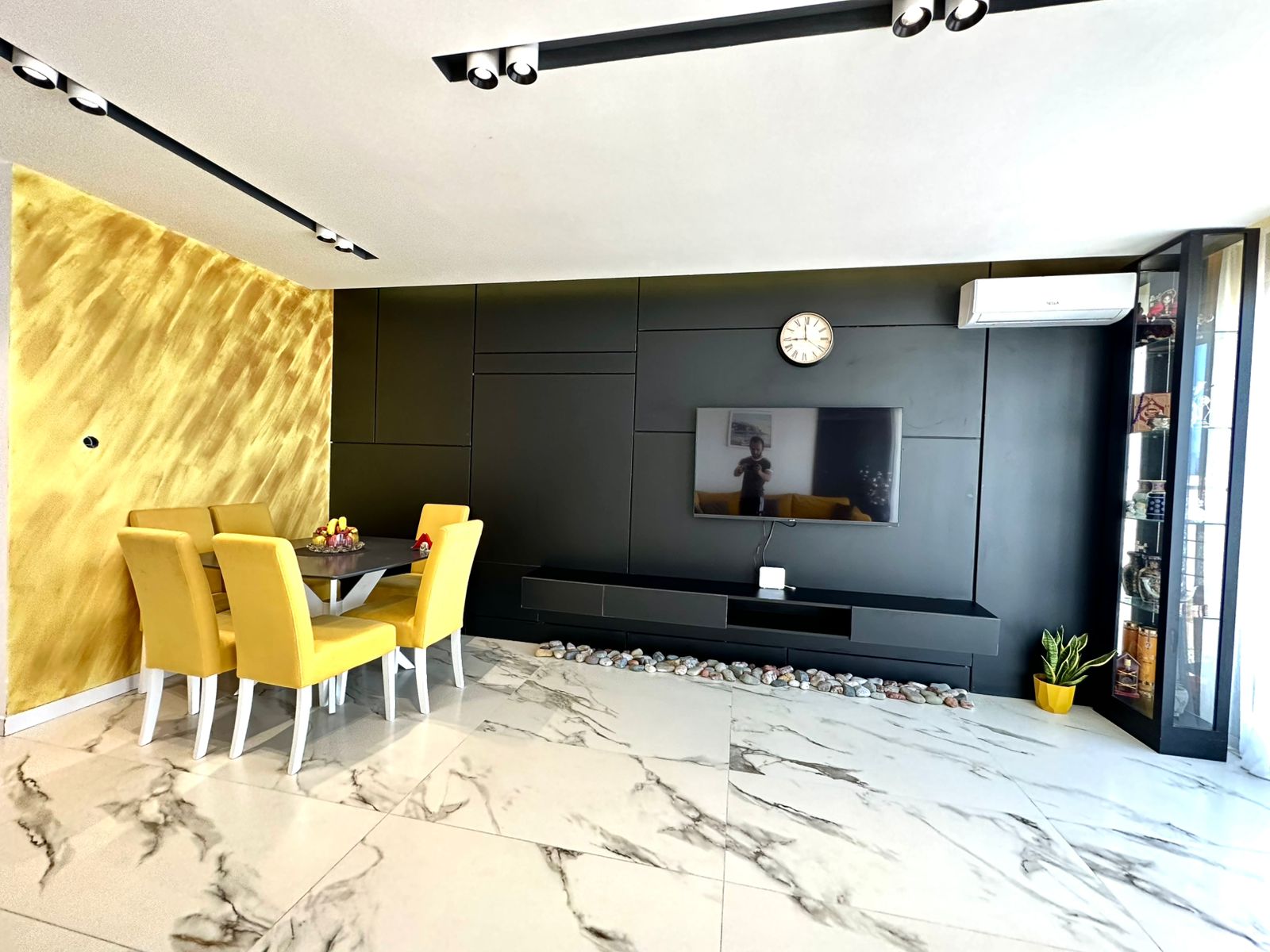 Elegant Ulcinj apartment: marble floors, stylish black accent wall, modern TV, dining area with yellow chairs&mdash;exclusive at montenegro-listings.me by ekosphere doo.
