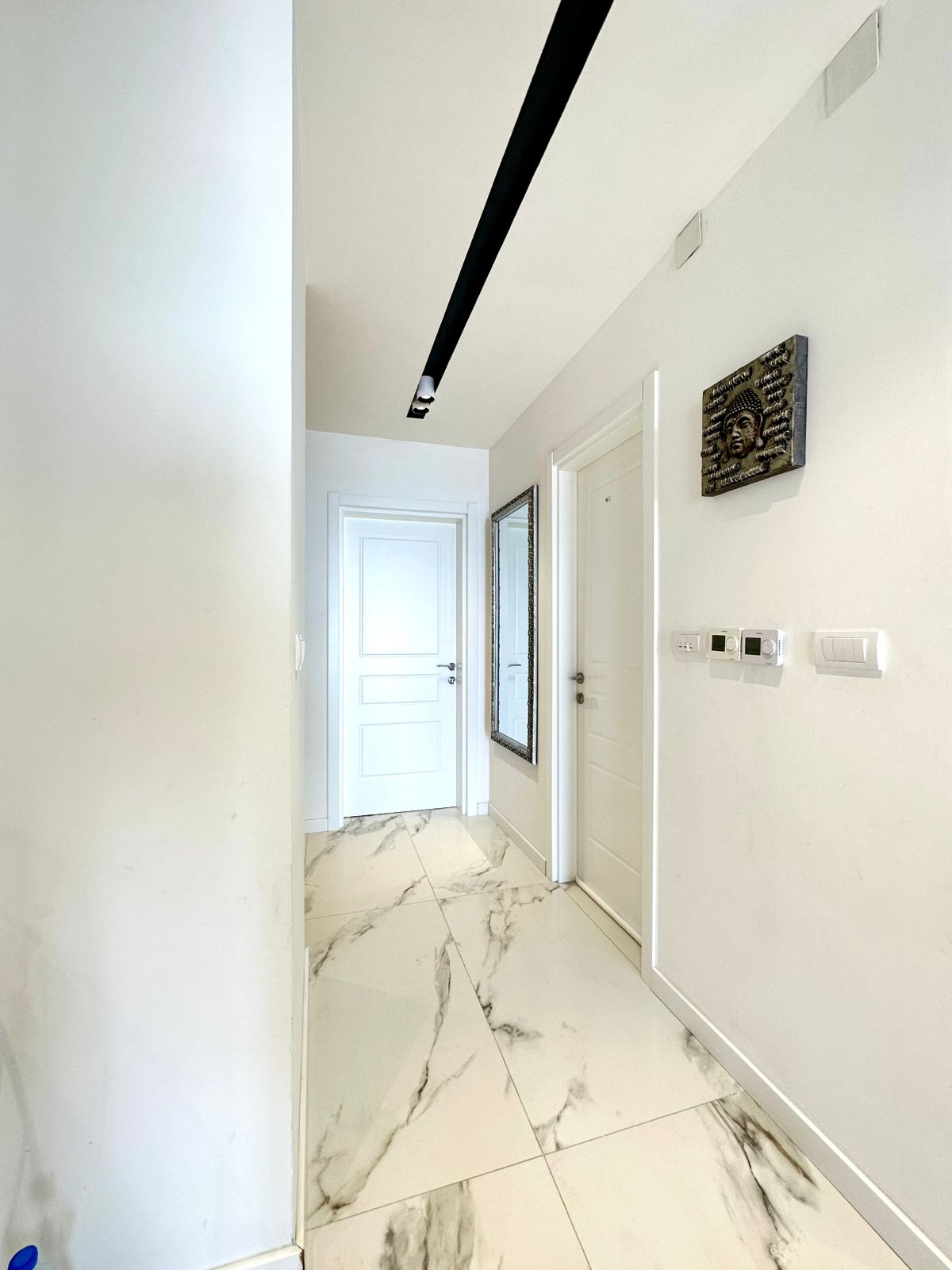Elegant hallway in Ulcinj property: bright, white walls, luxe marble floors, 3 doors&mdash;ideal Montenegro investment via montenegro-listings.me.