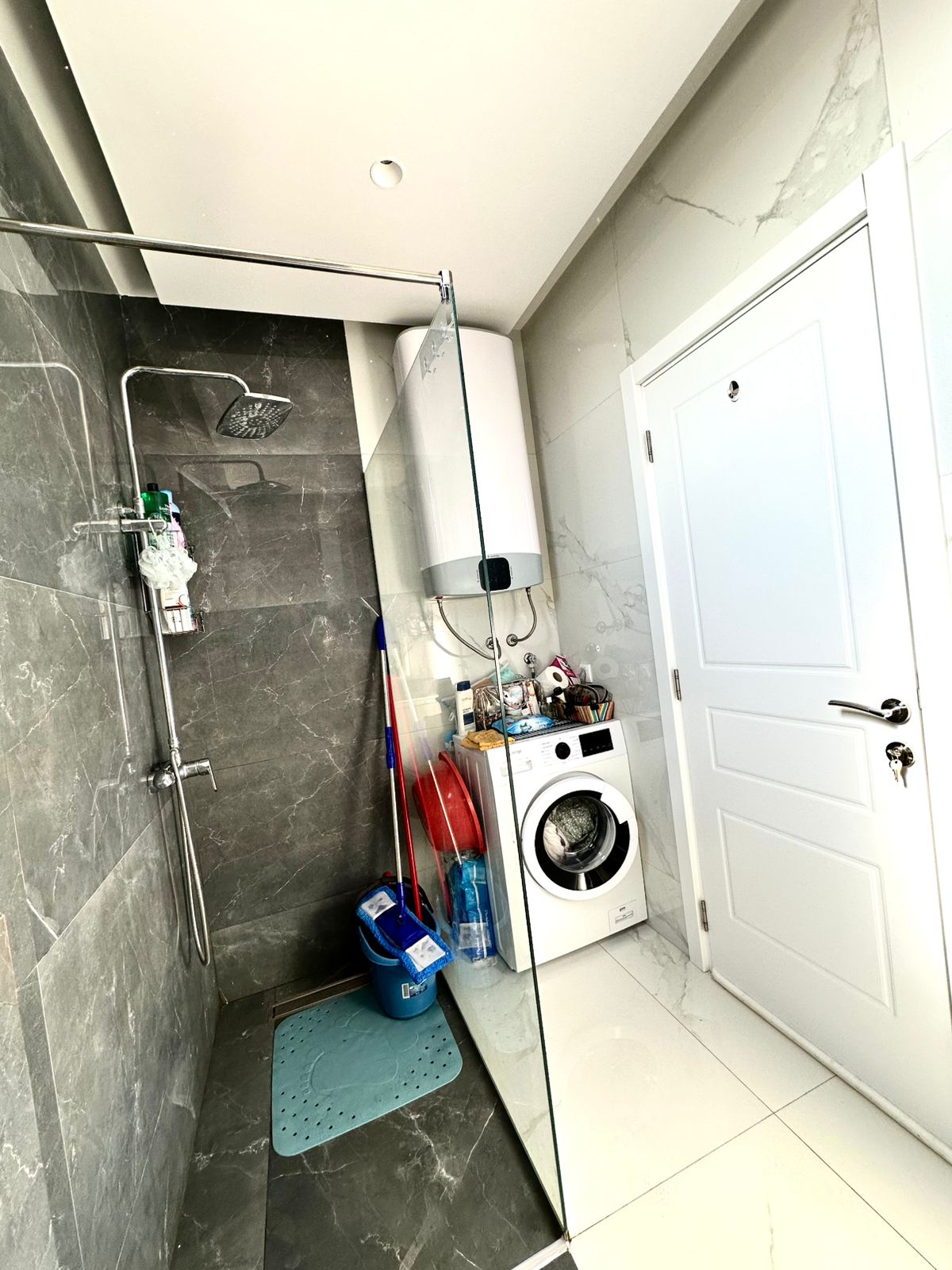 Modern Ulcinj bathroom: stylish gray tile shower, blue mat, washing machine, water heater. Prime investment&mdash;montenegro-listings.me by ekosphere doo.