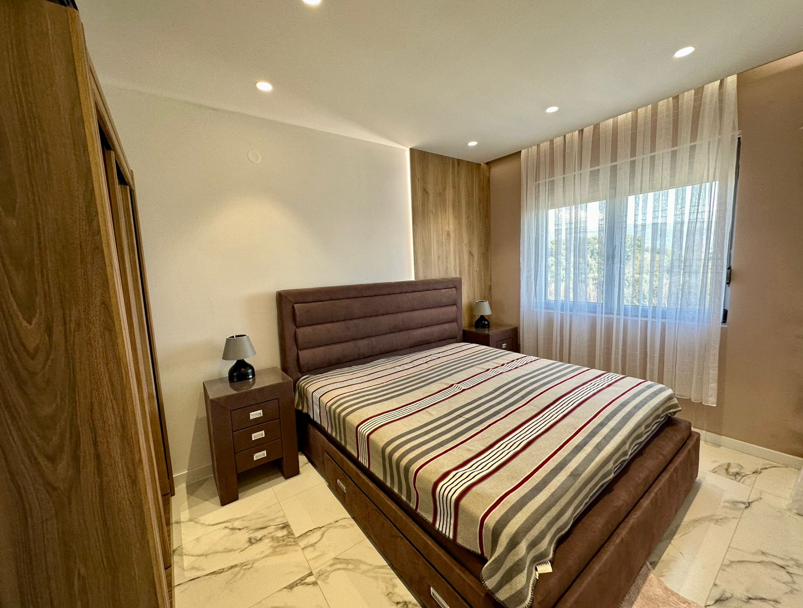 Elegant Ulcinj bedroom with marble floors, custom wardrobe, daylight window; ideal Montenegro property at montenegro-listings.me by ekosphere doo.