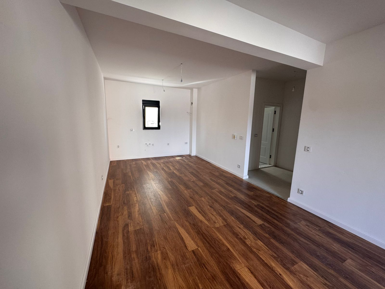 Spacious room in Ulcinj featuring white walls, dark wood flooring, and open layout&mdash;prime Montenegro investment via ekosphere doo.