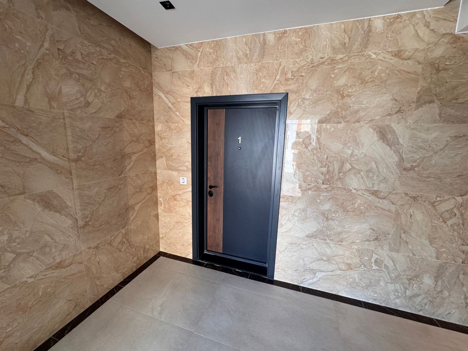 Modern black door with elegant brown accent, premium marble walls, and stylish tile flooring&mdash;ideal Ulcinj investment at montenegro-listings.me by ekosphere doo.
