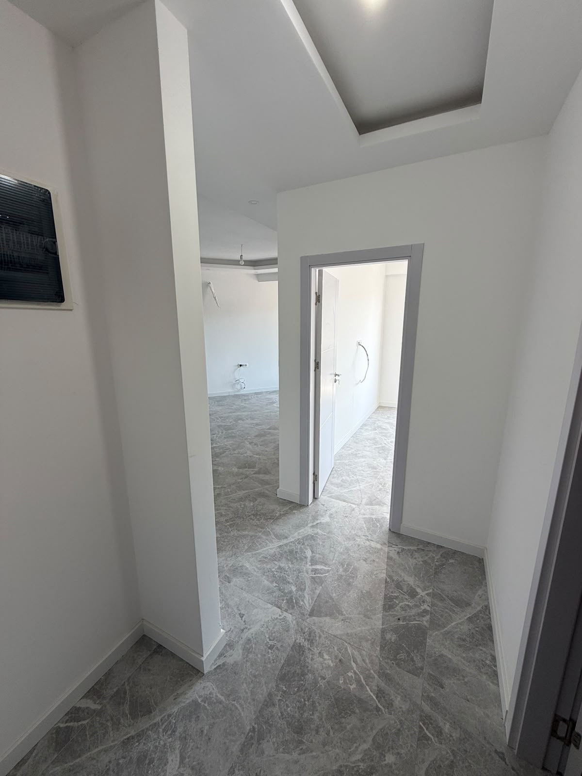 Discover exceptional investment potential in Ulcinj, Montenegro with this newly constructed property showcased exclusively on montenegro-listings.me, a project of ekosphere doo. Step into a spacious hallway featuring elegant gray marble flooring that leads to an inviting, sunlit room enriched by pristine white walls and modern recessed ceiling architecture. With visible construction elements offering the opportunity to customize and finish to your exact standards, this bright unfurnished space is perfect for buyers seeking prime real estate or lucrative rental investments in the dynamic Ulcinj property market.