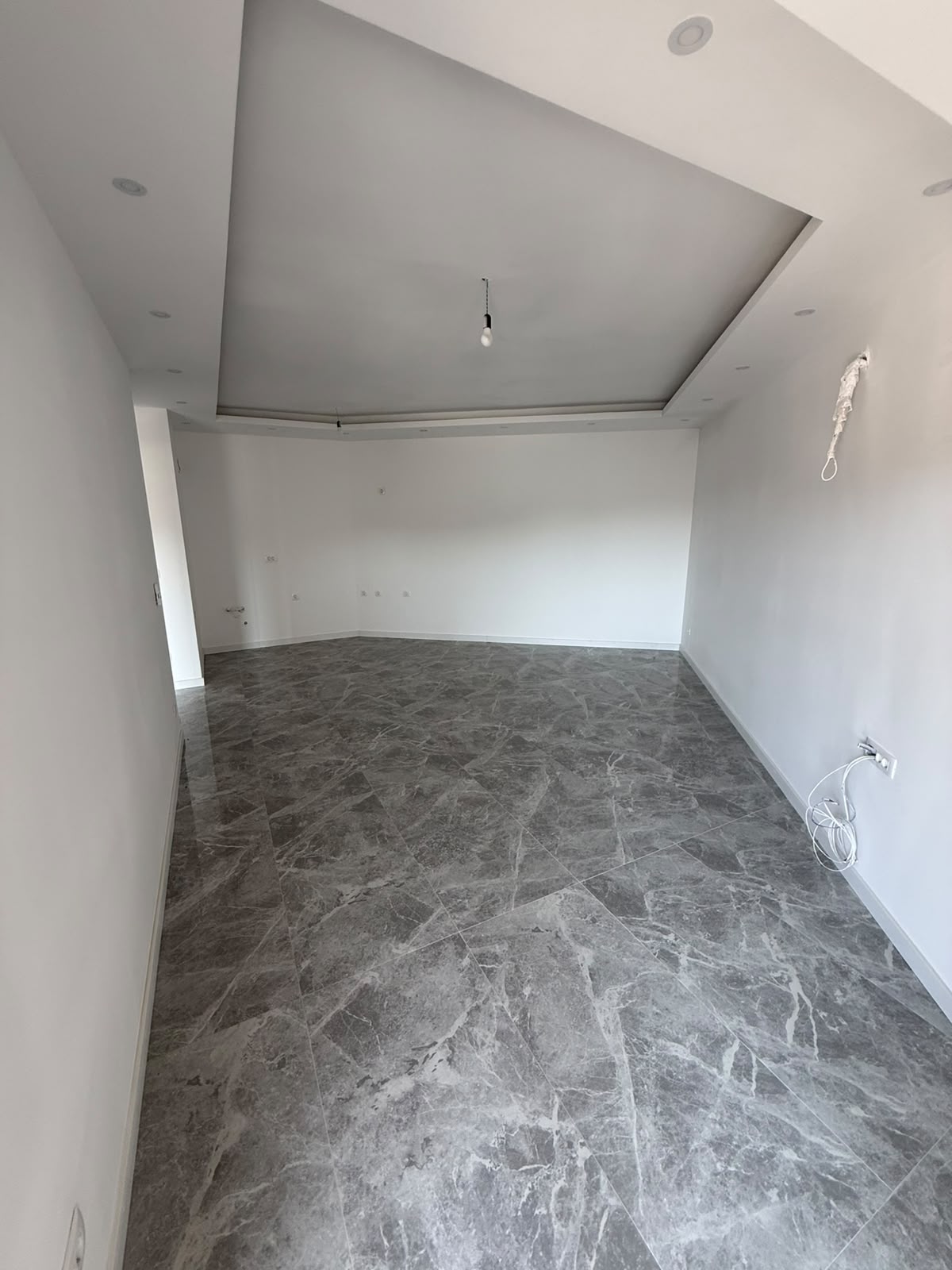 Discover exceptional investment potential in Ulcinj, Montenegro with this spacious, versatile room featuring elegant gray marble flooring and crisp white walls—ideal for customizing to your dream living or business space. The property boasts modern recessed ceiling lighting and a clean, unfinished layout ready for personal touches, including electrical fittings visible on the right wall. Perfect for investors or homeowners seeking value in the thriving Montenegro real estate market. Listed exclusively by montenegro-listings.me—a project of ekosphere doo in Ulcinj—this blank canvas offers an outstanding opportunity to secure prime property in a desirable coastal location.