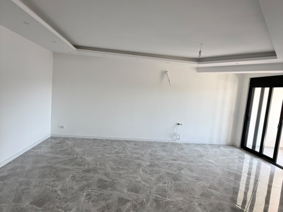 Bright and spacious empty room in Ulcinj, Montenegro, featuring pristine white walls, elegant gray marble flooring, and stylish black-framed sliding glass doors that invite abundant natural light. The modern white ceiling with recessed lighting adds to the airy ambiance, while conveniently placed electrical outlets and cabling offer practical flexibility. This well-lit property offers exceptional potential for investors or homebuyers seeking premium real estate in Ulcinj. Explore more high-value opportunities on montenegro-listings.me, a trusted project by ekosphere doo in Ulcinj.