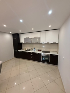 Discover a stylish, modern kitchen in Ulcinj, Montenegro, ideal for discerning property buyers and real estate investors. This contemporary space features sleek dark lower cabinets paired with elegant white upper cabinetry, a high-quality built-in oven, advanced electric cooktop, and a premium sink. The countertop is perfectly appointed with essential small appliances for convenience. Enjoy timeless beige tiled flooring and walls complemented by designer ceiling lights that create a warm and inviting atmosphere. Perfectly suited for those seeking an excellent investment or dream home in the Montenegro property market—available exclusively through montenegro-listings.me, a trusted project of ekosphere doo Ulcinj.