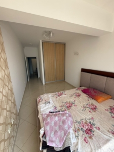 Spacious, well-maintained bedroom in Ulcinj, Montenegro, featuring a comfortable bed with elegant floral bedding, organized storage with a modern wooden closet and sliding doors, and easy-to-clean tiled flooring. Natural light flows from the open hallway for an inviting atmosphere. Perfect for property investors seeking attractive real estate opportunities or second homes in Ulcinj—listed exclusively on montenegro-listings.me by ekosphere doo.