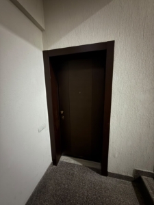 Discover this modern entrance with a stylish, dark brown door set against a pristine white textured wall, adjacent to a sleek staircase—a mark of quality craftsmanship in Ulcinj, Montenegro real estate. The solid door is equipped with a contemporary handle and convenient peephole for added security, while an accessible light switch highlights thoughtful design. Ideal for discerning investors seeking prime property opportunities in the competitive Ulcinj property market. Exclusively listed on montenegro-listings.me—a trusted project from ekosphere doo in Ulcinj—this entryway reflects the premium standards buyers expect when investing in Montenegro’s vibrant coastal region.