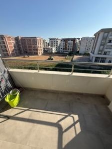 Discover an excellent investment opportunity in Ulcinj, Montenegro with this spacious balcony featuring elegant tiled flooring and secure railing. Enjoy panoramic views of ongoing residential development, highlighting the area’s growth potential and proximity to modern multi-story apartment complexes under a vibrant blue sky. The balcony provides ample space for outdoor leisure or utility, currently equipped with a drying rack and storage bucket. Secure your piece of Ulcinj real estate through montenegro-listings.me—a trusted project by ekosphere doo—where property value and future returns meet the beauty of coastal living.