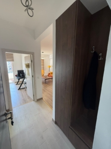 Step into this inviting Ulcinj property, presented by montenegro-listings.me—a project of ekosphere doo—perfectly positioned for both investment and comfortable living. The welcoming hallway features elegant light tile flooring and a sophisticated dark wooden closet, offering practical storage solutions. Through the open doorway, discover a sunlit living area complete with a modern desk, stylish chair, cozy sofa, and contemporary window blinds—ideal for relaxation or remote work. This move-in-ready apartment in Ulcinj seamlessly blends functionality with tasteful design, making it an exceptional opportunity in the Montenegro real estate market.