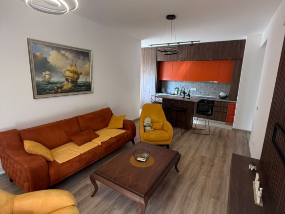 Experience contemporary coastal living in this stylish Ulcinj property, exclusively listed on montenegro-listings.me—a project of ekosphere doo. The spacious open-plan living room features vibrant orange and yellow seating, a sleek wooden coffee table, and a wall-mounted TV—perfect for relaxing or entertaining guests. The modern kitchen boasts striking red cabinets, ideal for culinary enthusiasts. Nautical-inspired artwork and elegant decorative lighting add sophisticated touches to this inviting space. Invest in premium Montenegro real estate with excellent rental potential right at the heart of Ulcinj’s thriving property market.