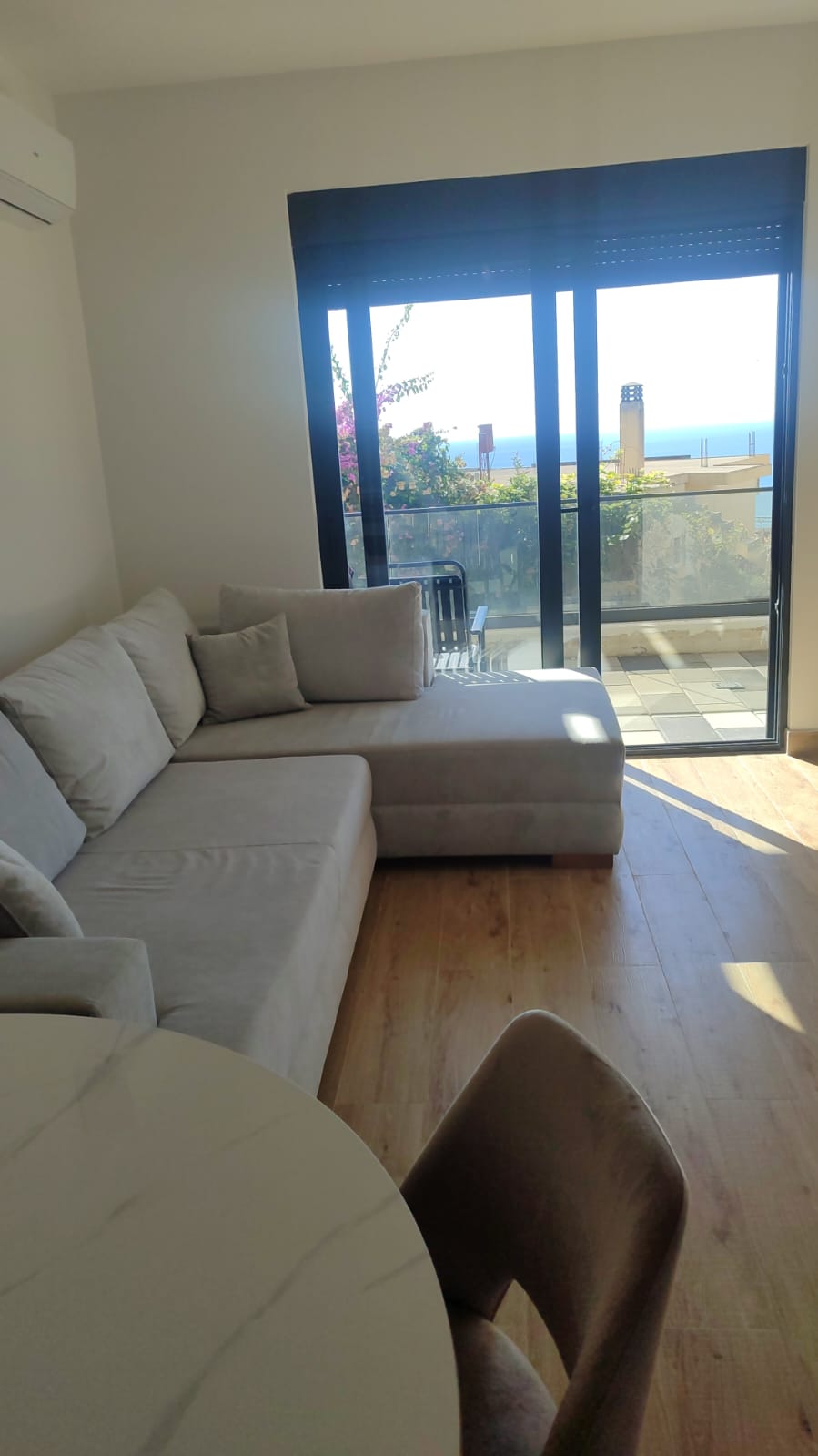 Experience modern coastal living in this stunning Ulcinj apartment, featuring a spacious and bright living room with a stylish light gray L-shaped sofa, elegant wood flooring, and a contemporary round marble dining table with chairs. Floor-to-ceiling glass doors seamlessly open to a private balcony boasting breathtaking sea views—perfect for relaxation or entertaining. This premium property is an exceptional real estate investment opportunity in Montenegro’s sought-after Ulcinj region. Discover more exclusive listings like this at montenegro-listings.me—a trusted project of ekosphere doo in Ulcinj—offering you the best in Montenegrin coastal real estate.