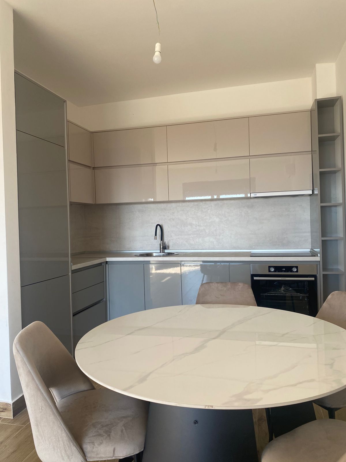 Upgrade your lifestyle with this elegant, modern kitchen in Ulcinj, Montenegro—featuring stylish glossy beige cabinets, a premium built-in oven, and a contemporary stainless steel sink. The spacious dining area boasts a sophisticated round marble table complemented by four matching beige chairs, perfect for entertaining or family gatherings. A minimalist exposed light bulb adds an urban-chic touch to the inviting ambiance. This beautifully designed kitchen offers an ideal investment opportunity and is exclusively listed on montenegro-listings.me—a trusted project of ekosphere doo delivering value in the desirable Ulcinj property market.