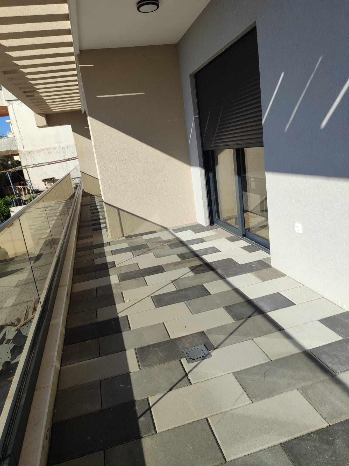 Experience modern Mediterranean living with this stylish tiled balcony in Ulcinj, Montenegro, featuring premium gray tiles in varying shades and a sleek glass railing that maximizes natural light. The balcony’s spacious layout and contemporary design, highlighted by a closed dark roller shutter and elegant sunlit patterns on the floor and wall, offer an ideal setting for relaxation or entertaining guests. Invest confidently in the Ulcinj property market with montenegro-listings.me—a project of ekosphere doo—your trusted real estate platform for exclusive coastal properties and smart investment opportunities.